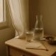 Verre et carafe d'eau, éventail en bois et bol de tisane sur une table de chevet près d'une fenêtre
