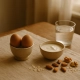 Bol d'œufs, yaourt nature, amandes, noix et flocons d'avoine disposés sur une table en bois